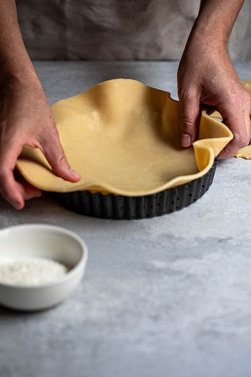 Plano de 45° de los manos forrando el molde para tarta dulce