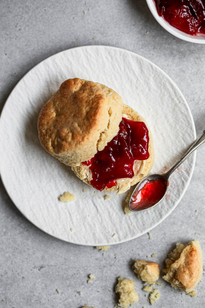 A scone on a plate with butter and marmalade