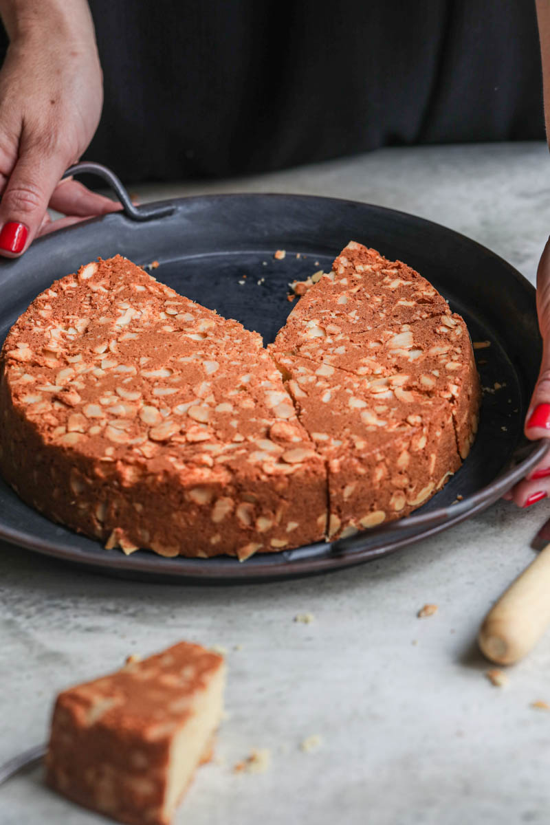 2 hands holding the tray with the almond paste cake.