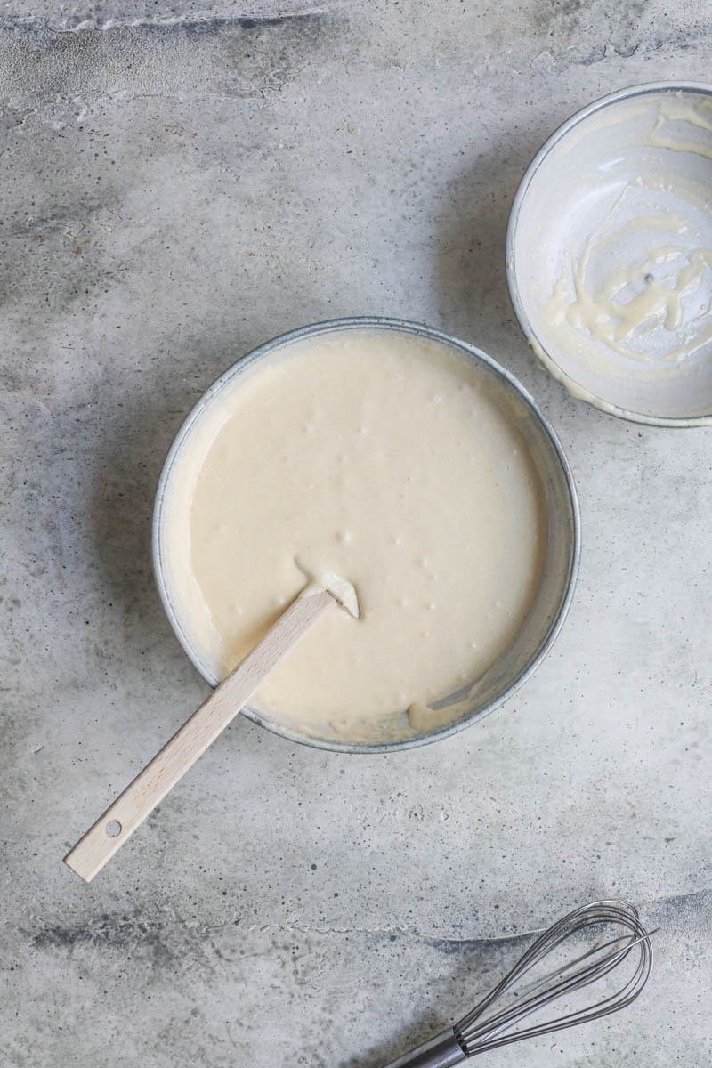 The almond cake batter inside a grey bowl with a spatula on the side.