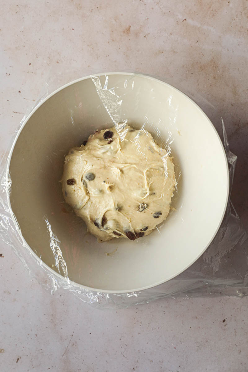 Ferment the Kugelhopf bread: the dough inside a beige bowl covered with a saran wrap.