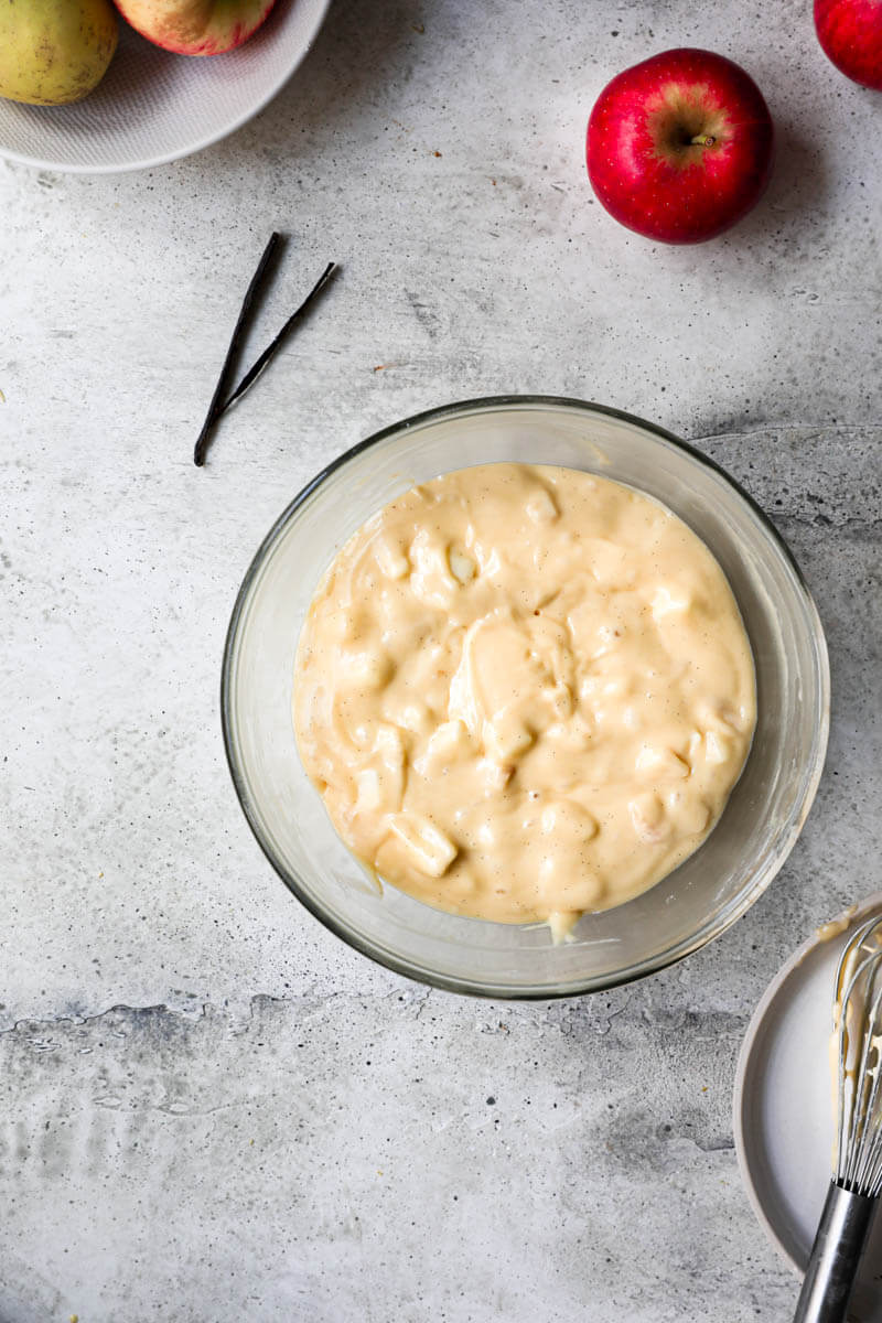 Overhead shot of a glass bowl with the cake batter with the apples folded in