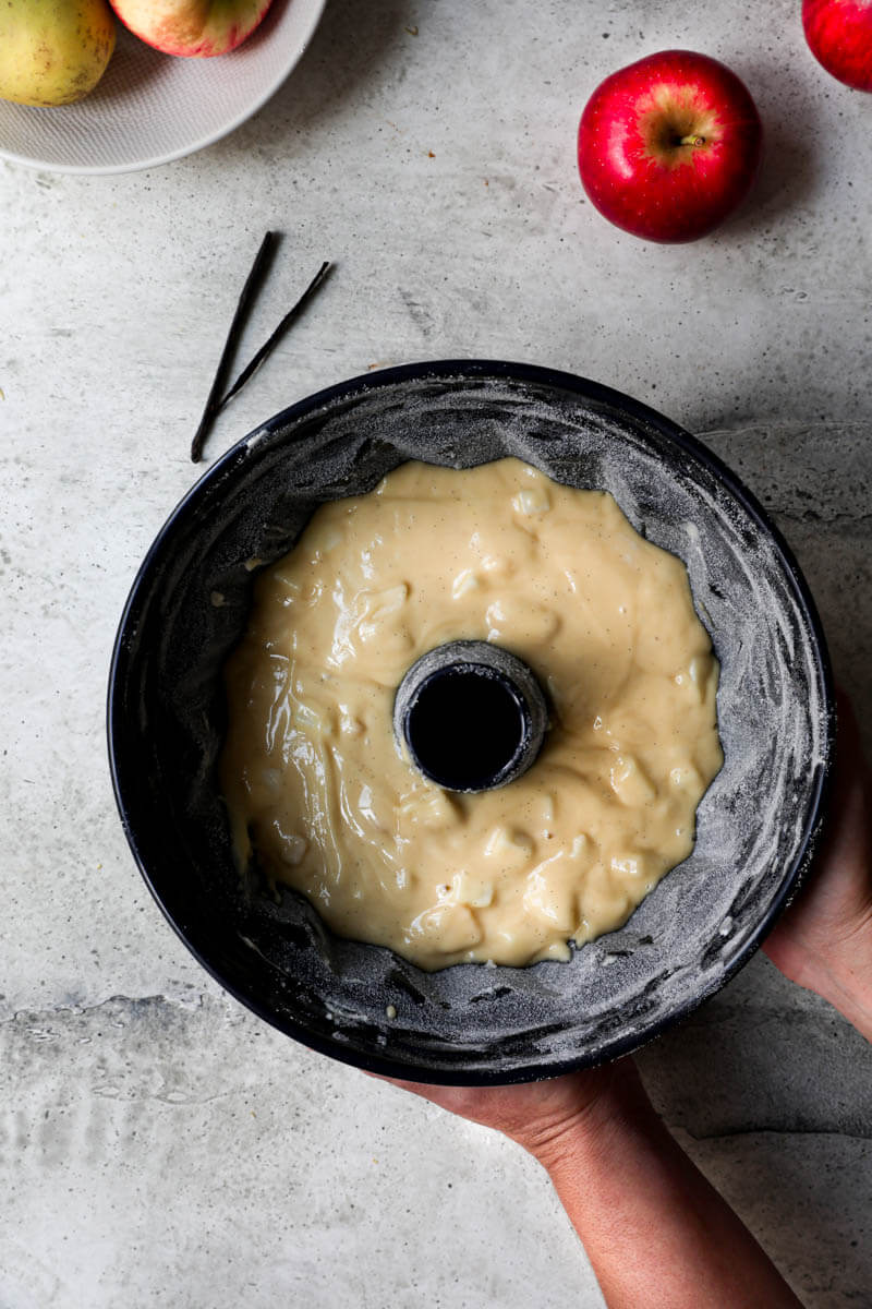 Overhead shot of 2 hands holding the cake pan ready for the oven