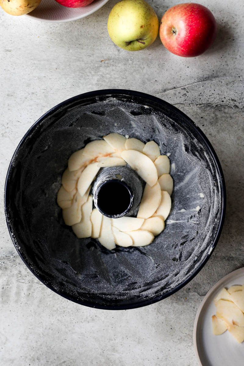 Overhead shot of the cake mould with sliced apples at the bottom