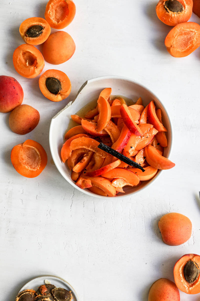 Overhead shot of apricots cut in different shapes some of them inside a bowl.