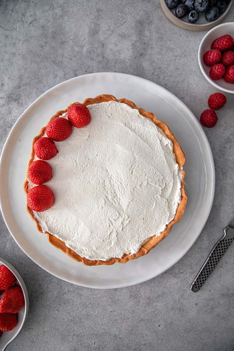 Overhead shot of the tart in process of being topped with berries