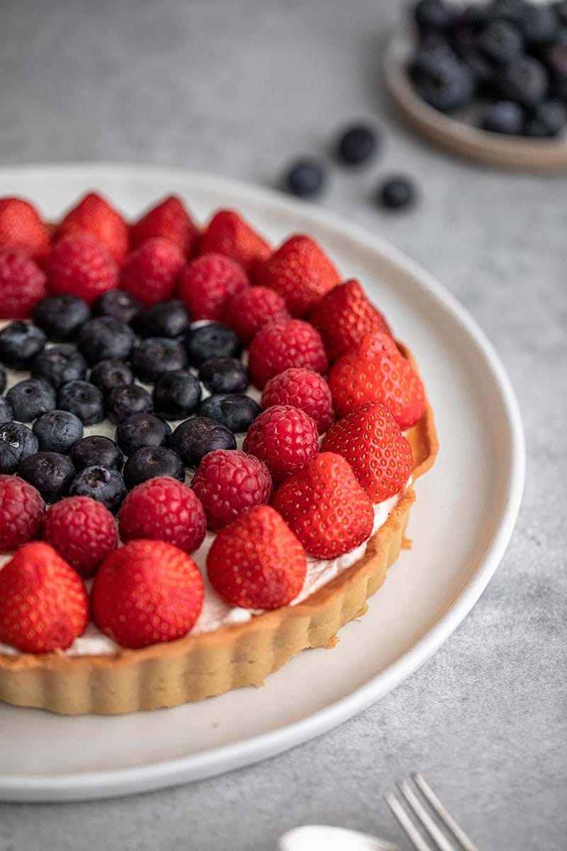 45° shot of half of the berry tart on a white serving plate