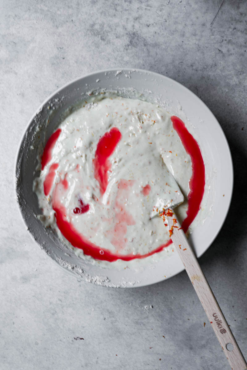 Cake batter in a white bowl with the added blood orange juice.