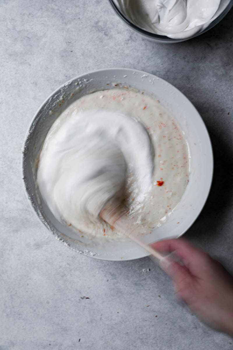 One hand folding in the whipped cream to the batter.