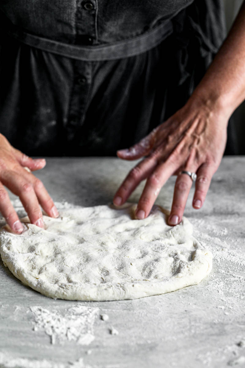 45° shot of 2 hands stretching the pizza dough