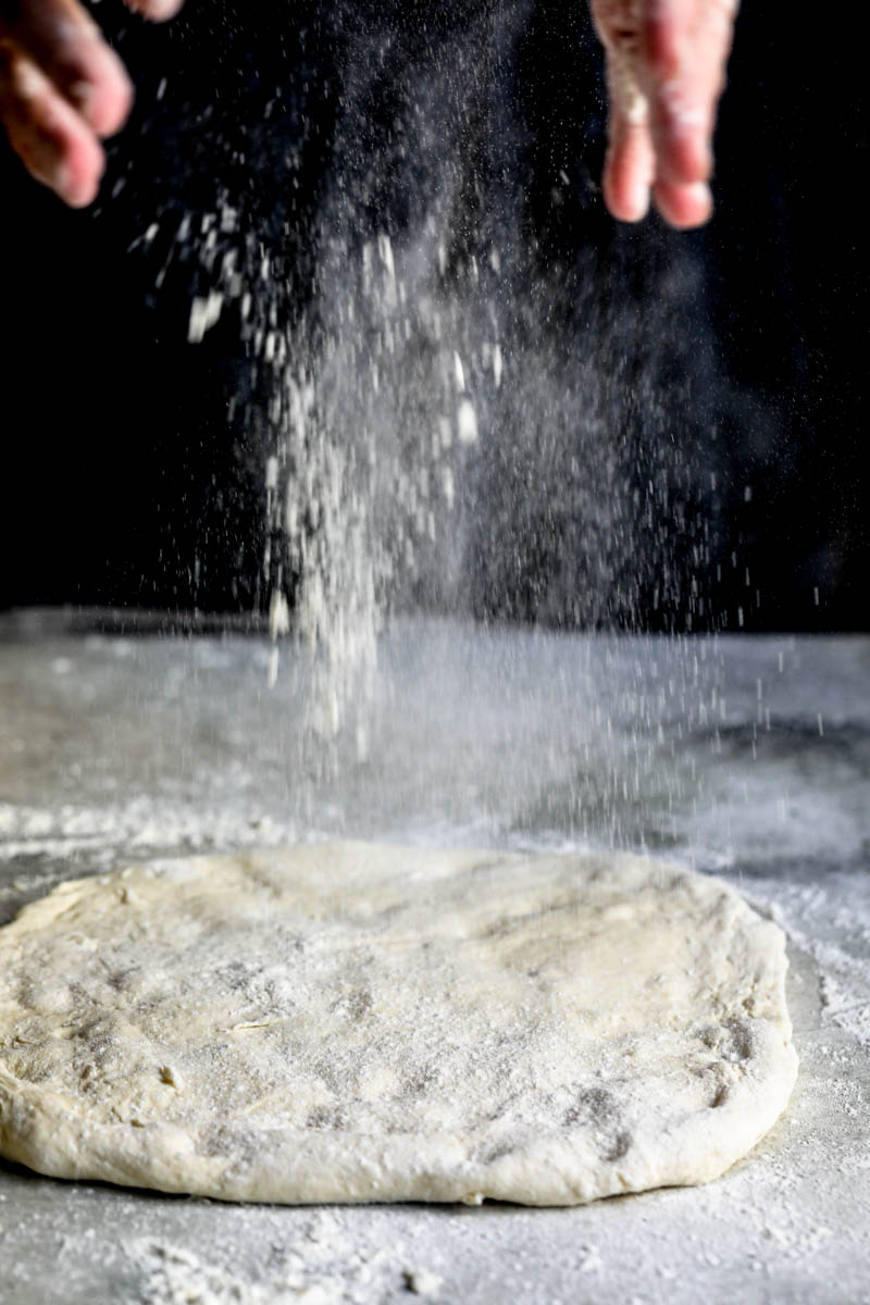 90° of 2 hands flouring the pizza dough