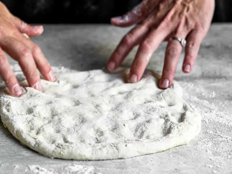 45° shot of 2 hands stretching the pizza dough