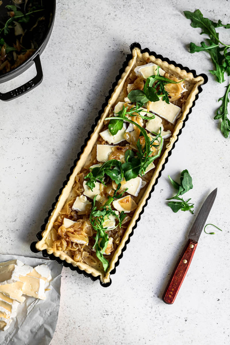 Overhead shot of the quiche crust filled with caramelized onions and brie cheese