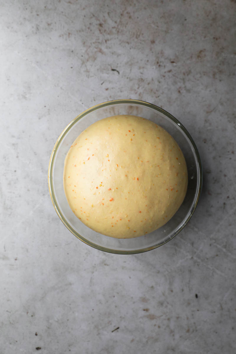 The easter bread dough after proving inside a glass bowl.