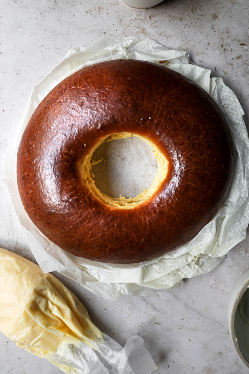 The baked Easter bread with a piping bag full of pastry cream on the side.