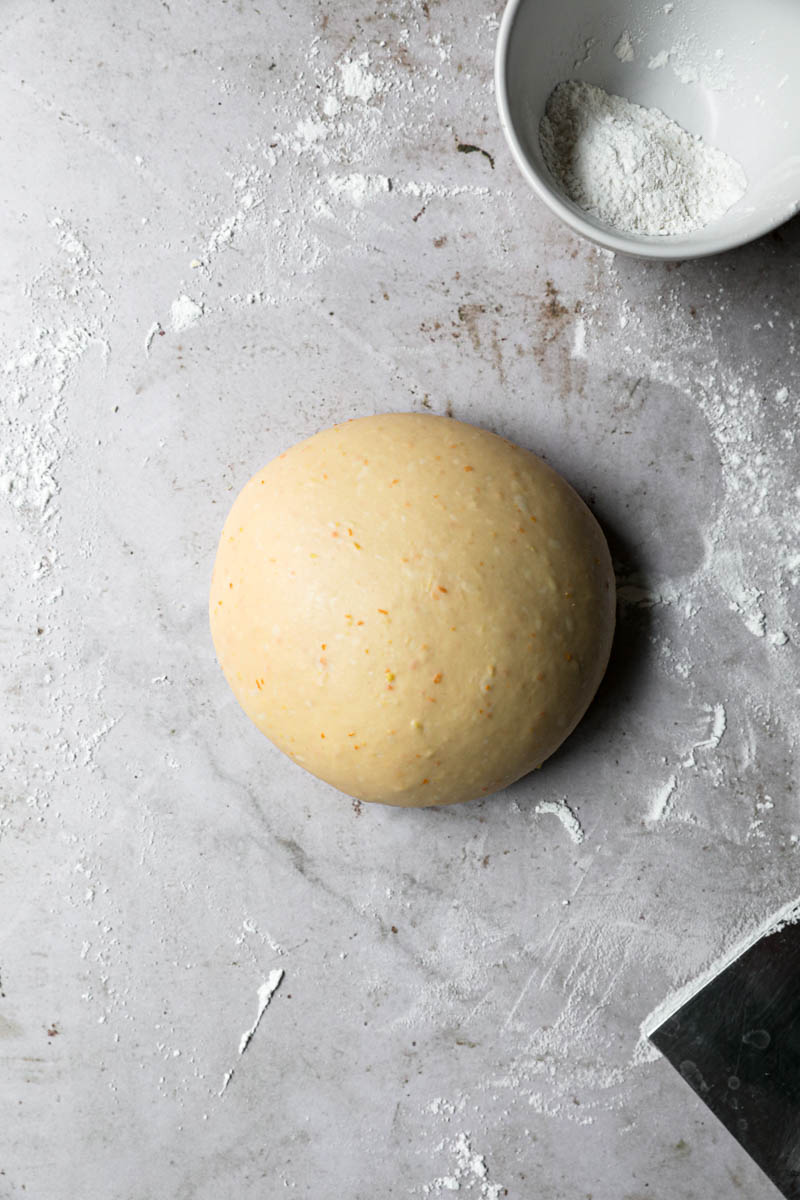 Easter bread dough shaped into a ball on the counter with flour around.