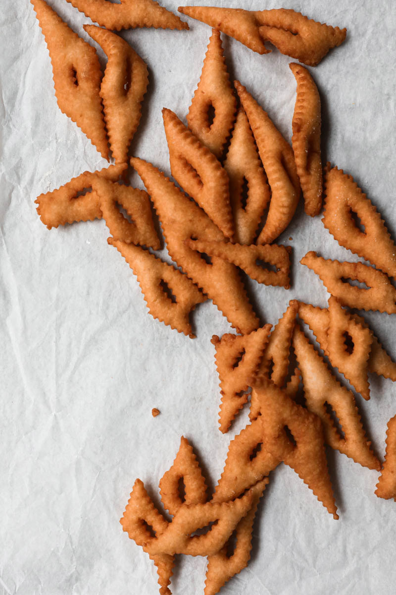 Deep fried bugnes on a piece of parchment paper