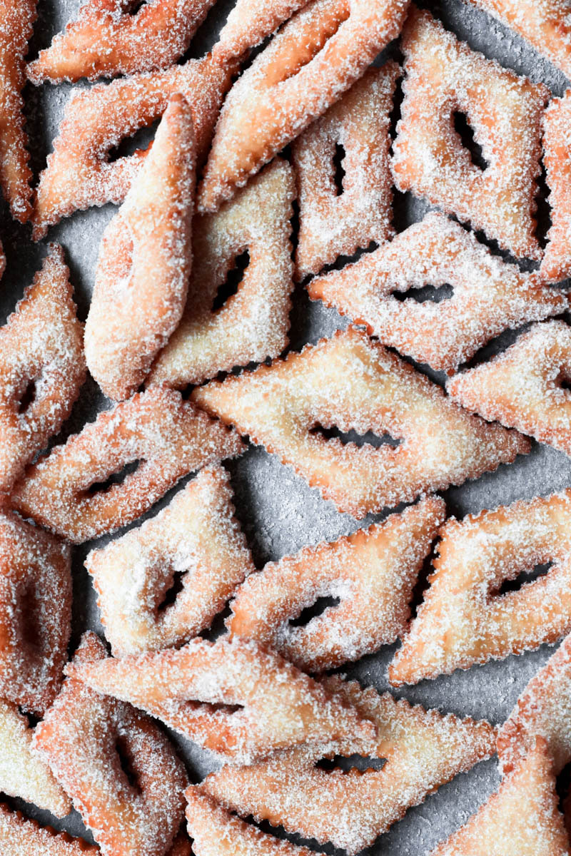 Bugnes rolled in sugar on a piece of parchment paper