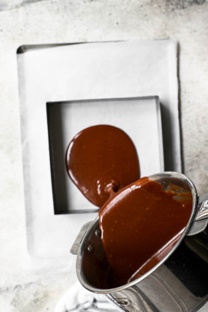 One hand pouring the caramel candy over the lined mould