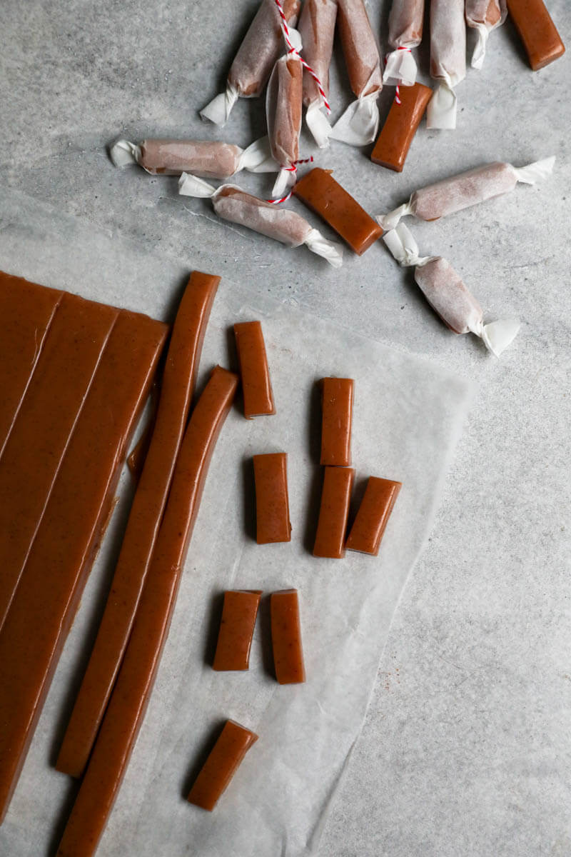 Sliced caramel candy on a piece of parchment paper and other candy bars wrapped