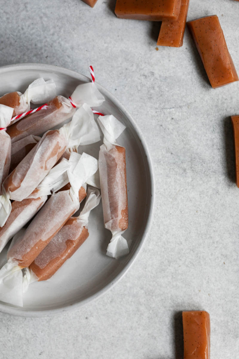 Wrapped caramel candies on a small plate with others around it