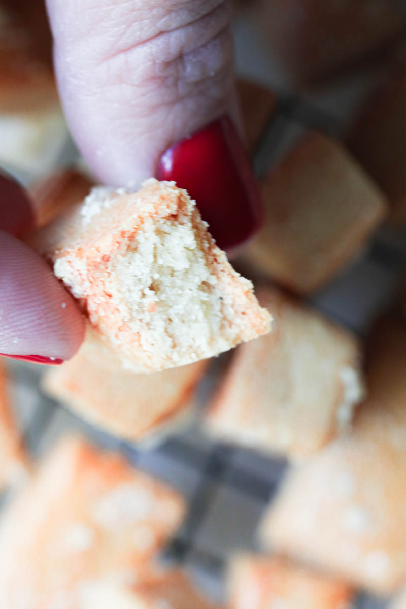 One hand holding one parmesan cheese cookie showing off the inside.