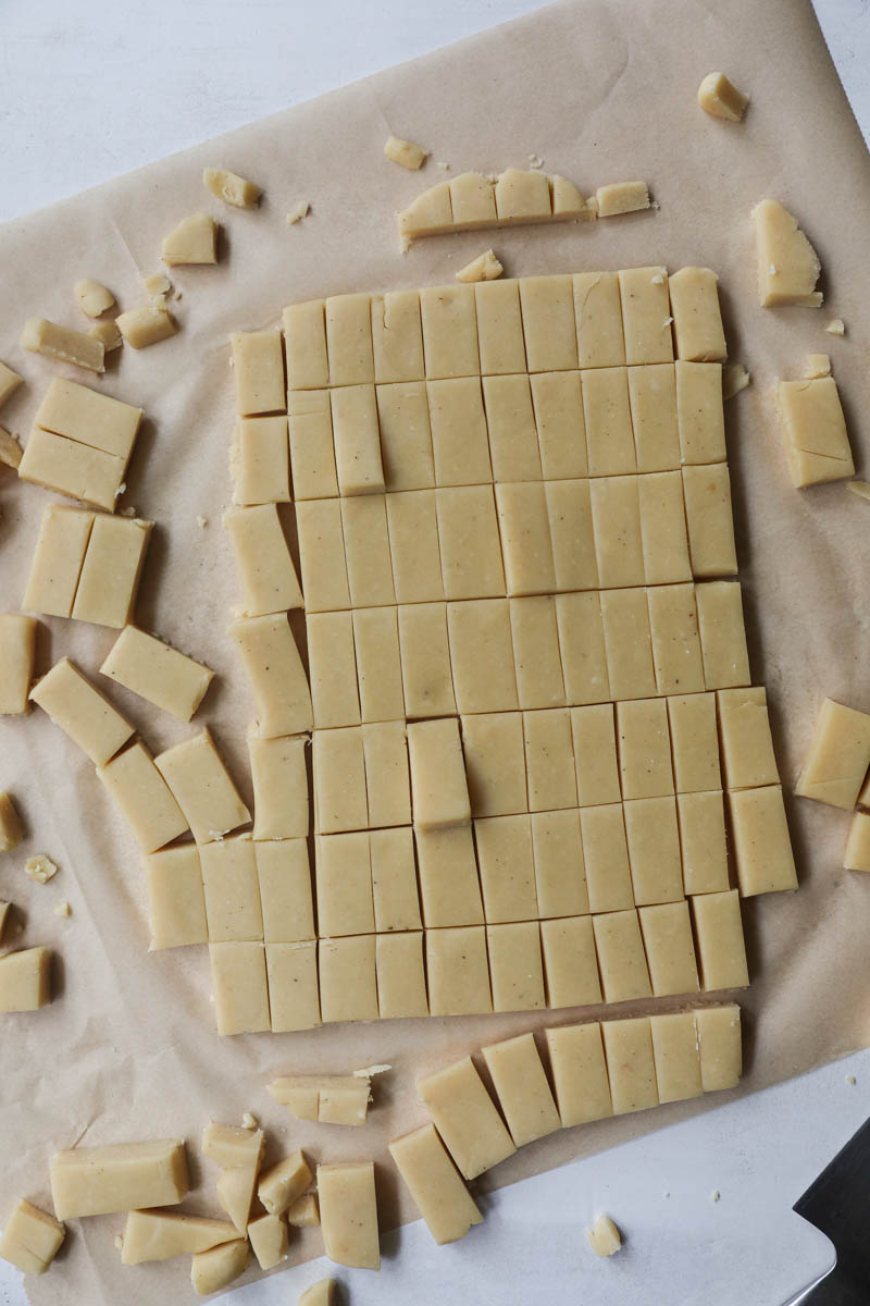 The rolled out parmesan cheese cookie dough over a parchment paper cut into rectangles.