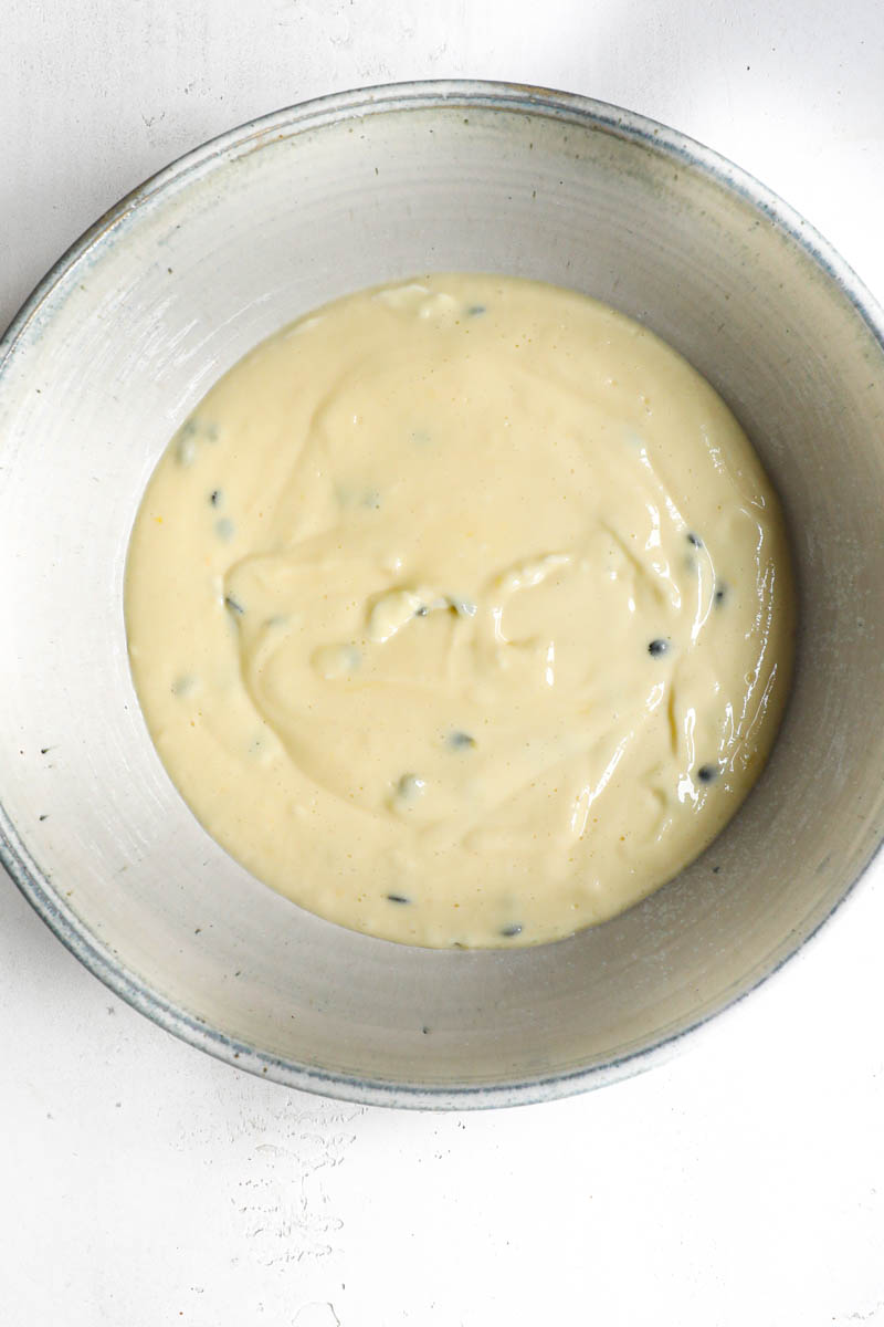 The passion fruit cheesecake batter in the making inside a grey bowl.