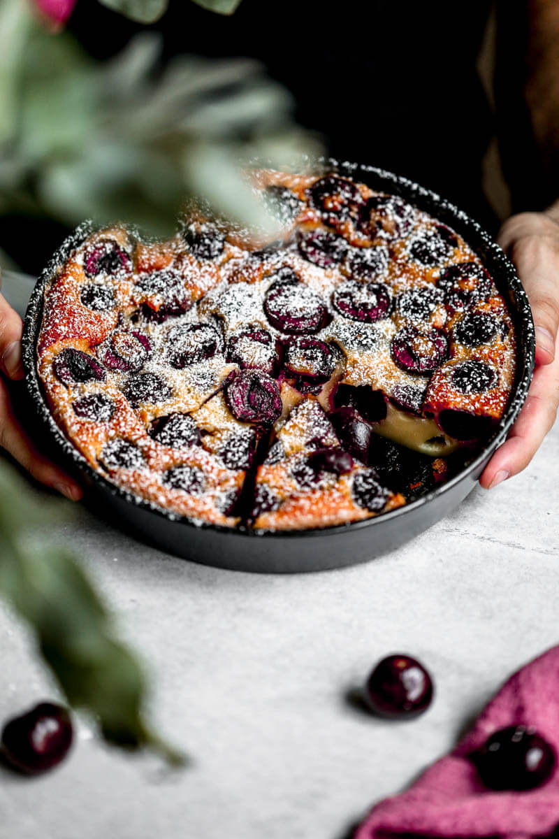 45° shot of 2 hands holding the cherry clafoutis