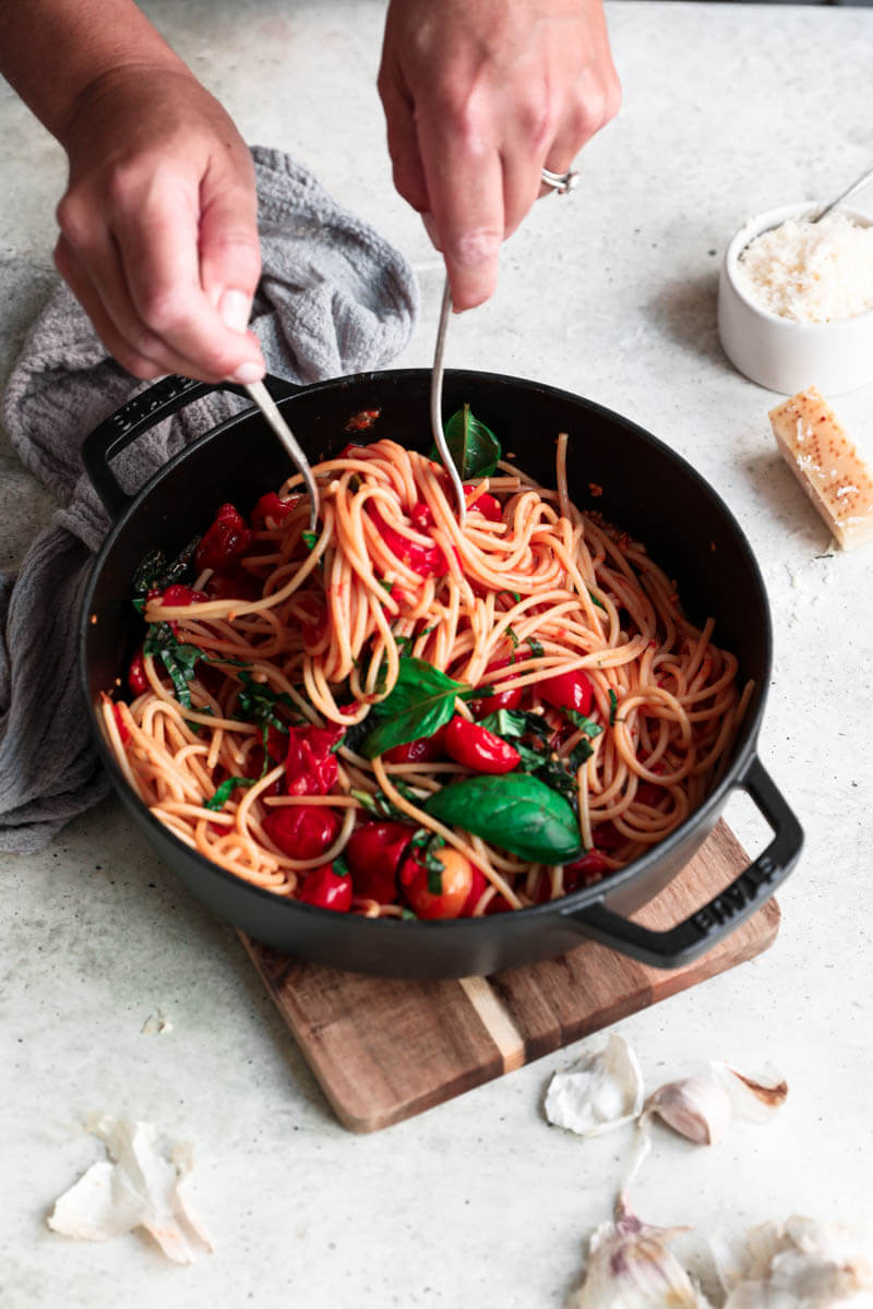 45° shot of 2 hands serving the cherry tomato pasta