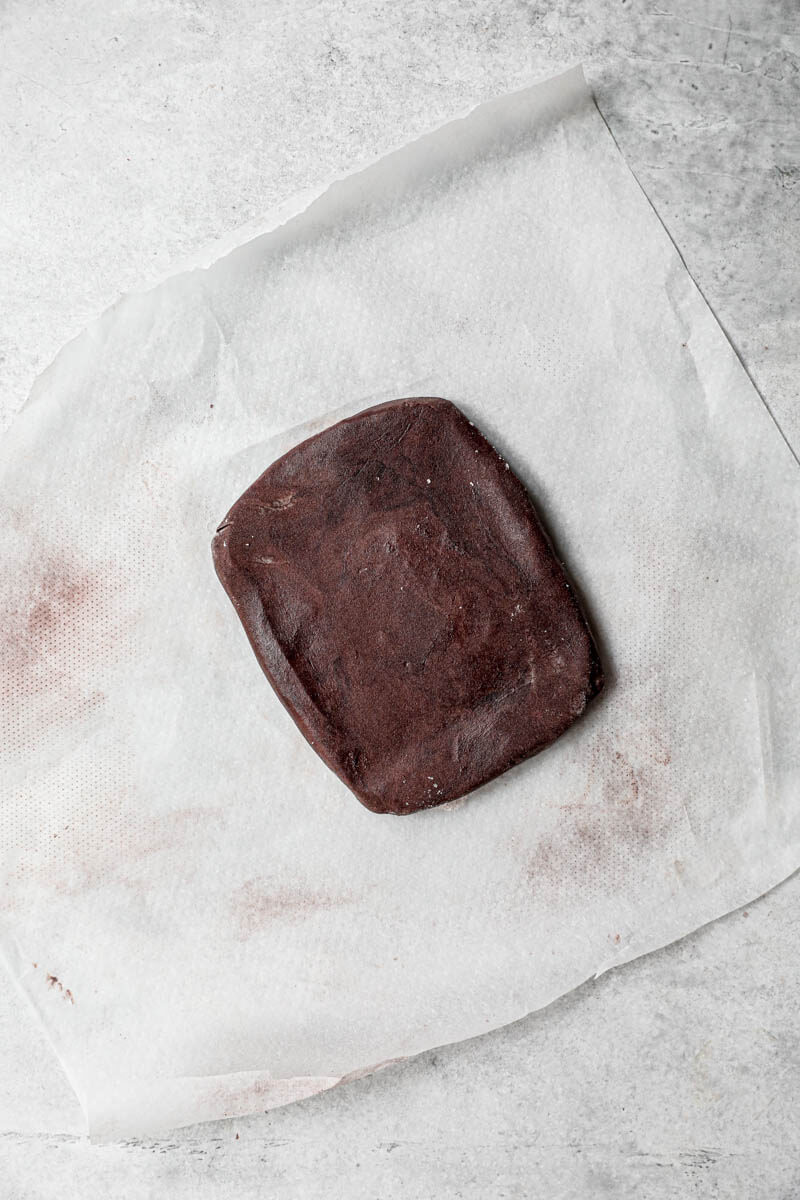 Overhead shot of the shortbread chocolate dough shaped as a rectangle on a piece of parchment paper