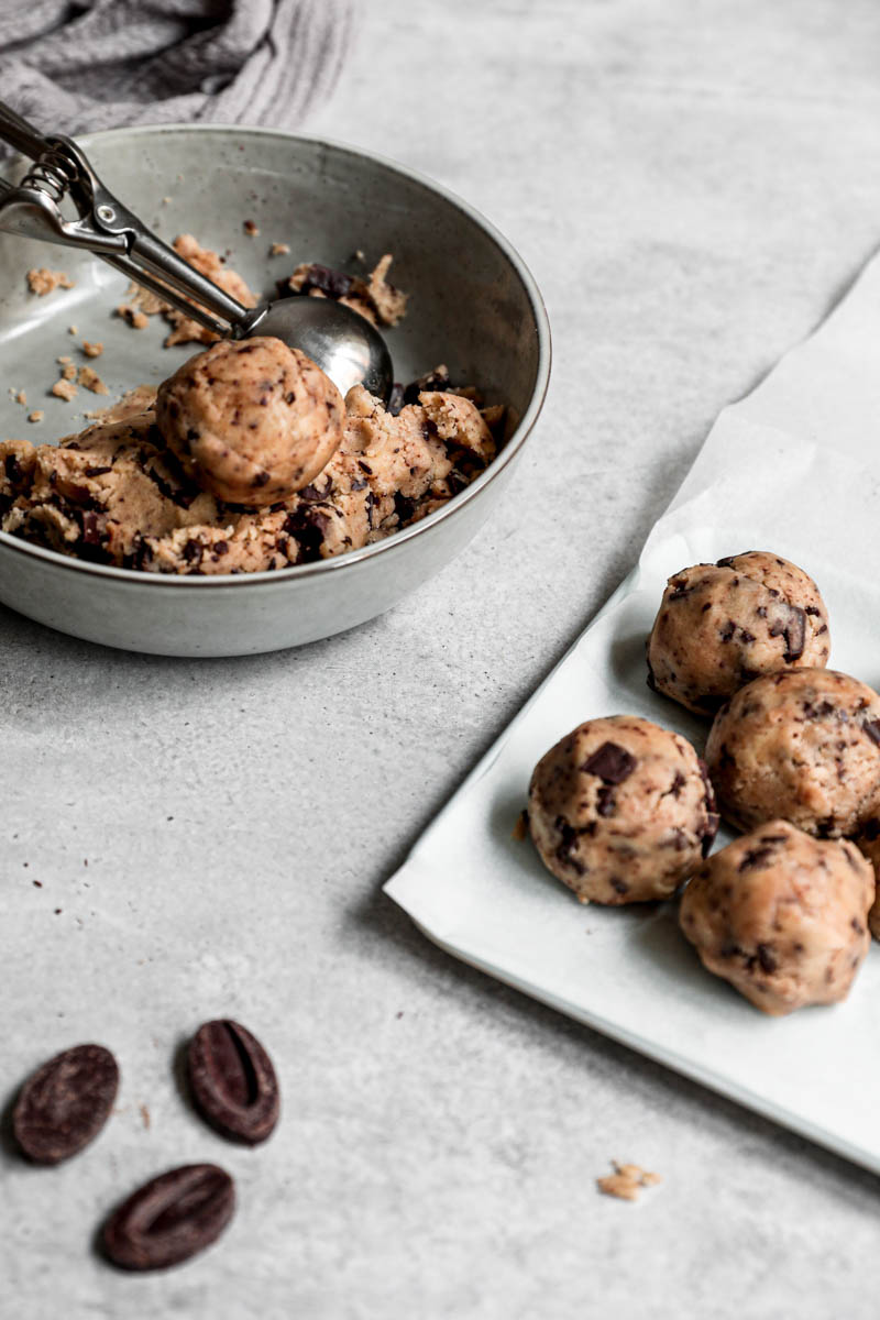 45° shot of the cookie dough in a bowl and the cookies on a baking tray