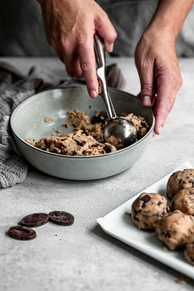 45° shot of a hand scooping the cookie dough