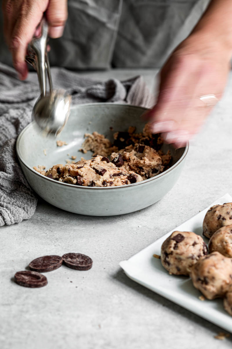 45° shot of a hand scooping the cookie dough