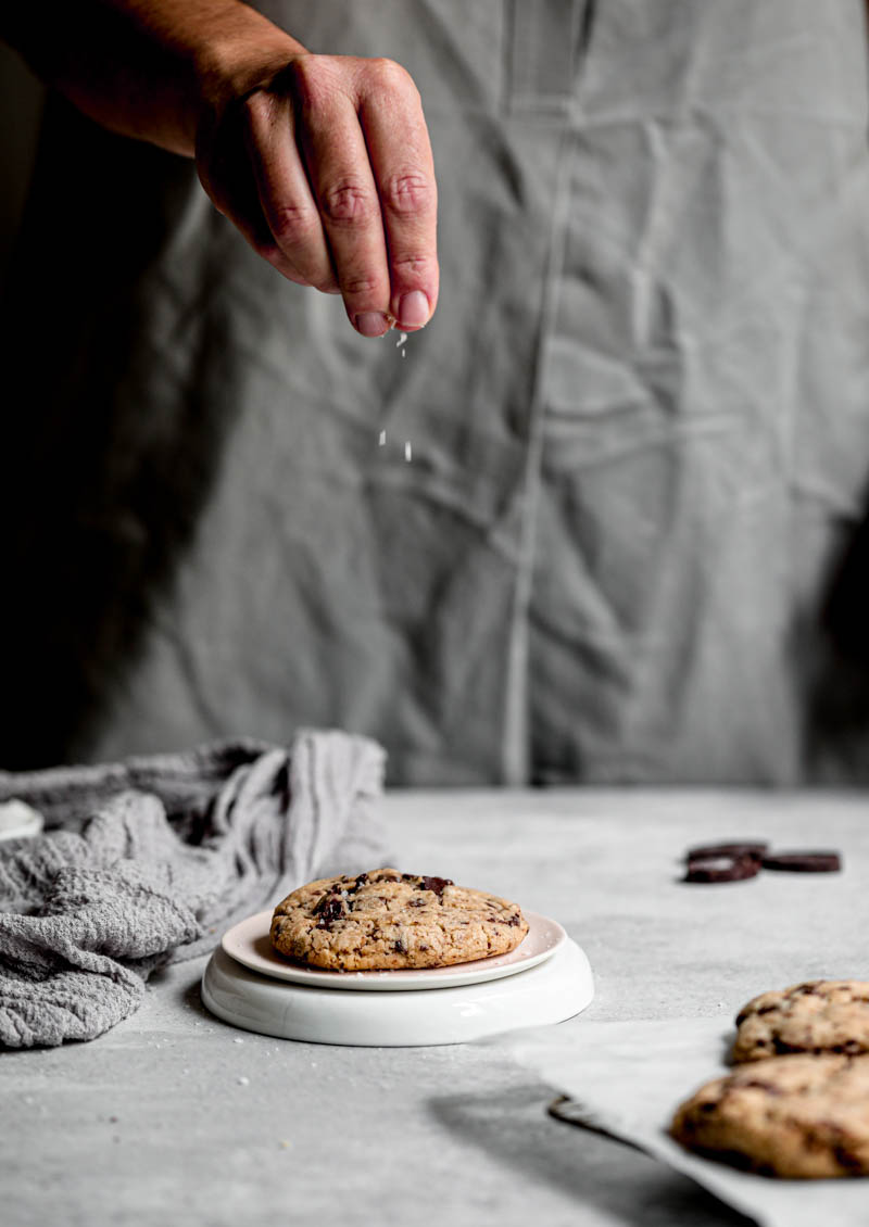 90° shot of a hand sprinkling salt onto one cookie