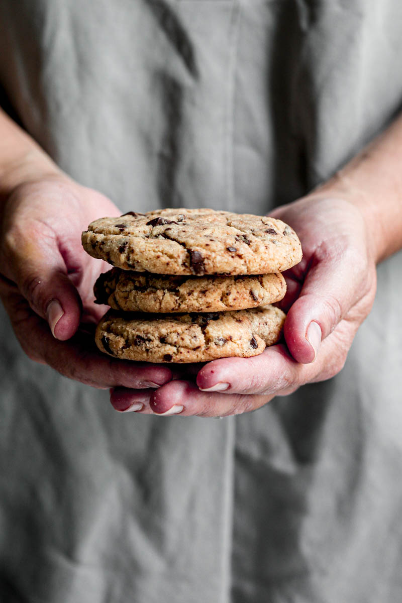 90° shot of 2 hands holding 3 cookies