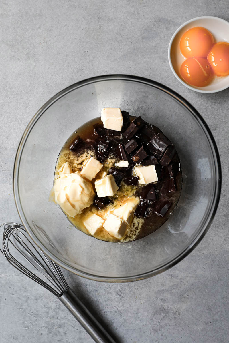 Chocolate and butter melting away in a sugar syrup inside a glass bowl.