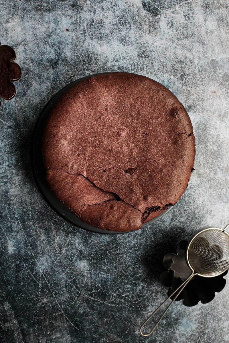 The chocolate fudge cake just removed from the oven with a small bowl with cocoa on the side.