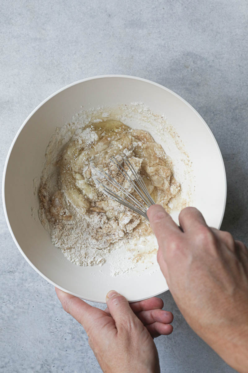 2 hands whisking the egg whites into the cake batter.