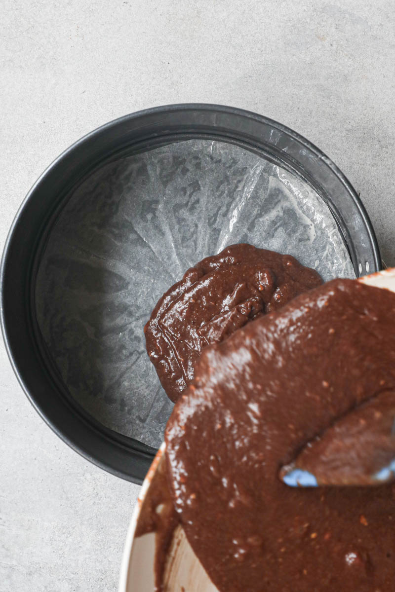Pouring the chocolate hazelnut cake batter onto the lined baking pan.