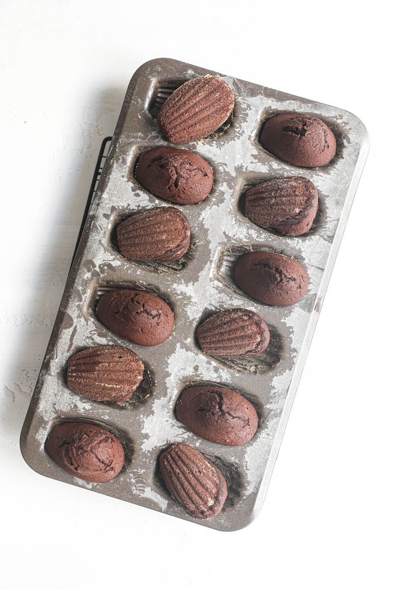 THe baked chocolate madeleines truned over inside the baking tray.