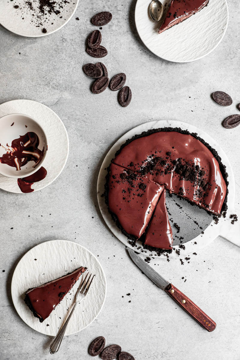 Overhead shot of the sliced chocolate mousse pie surrounded by white plates and pieces of chocolate