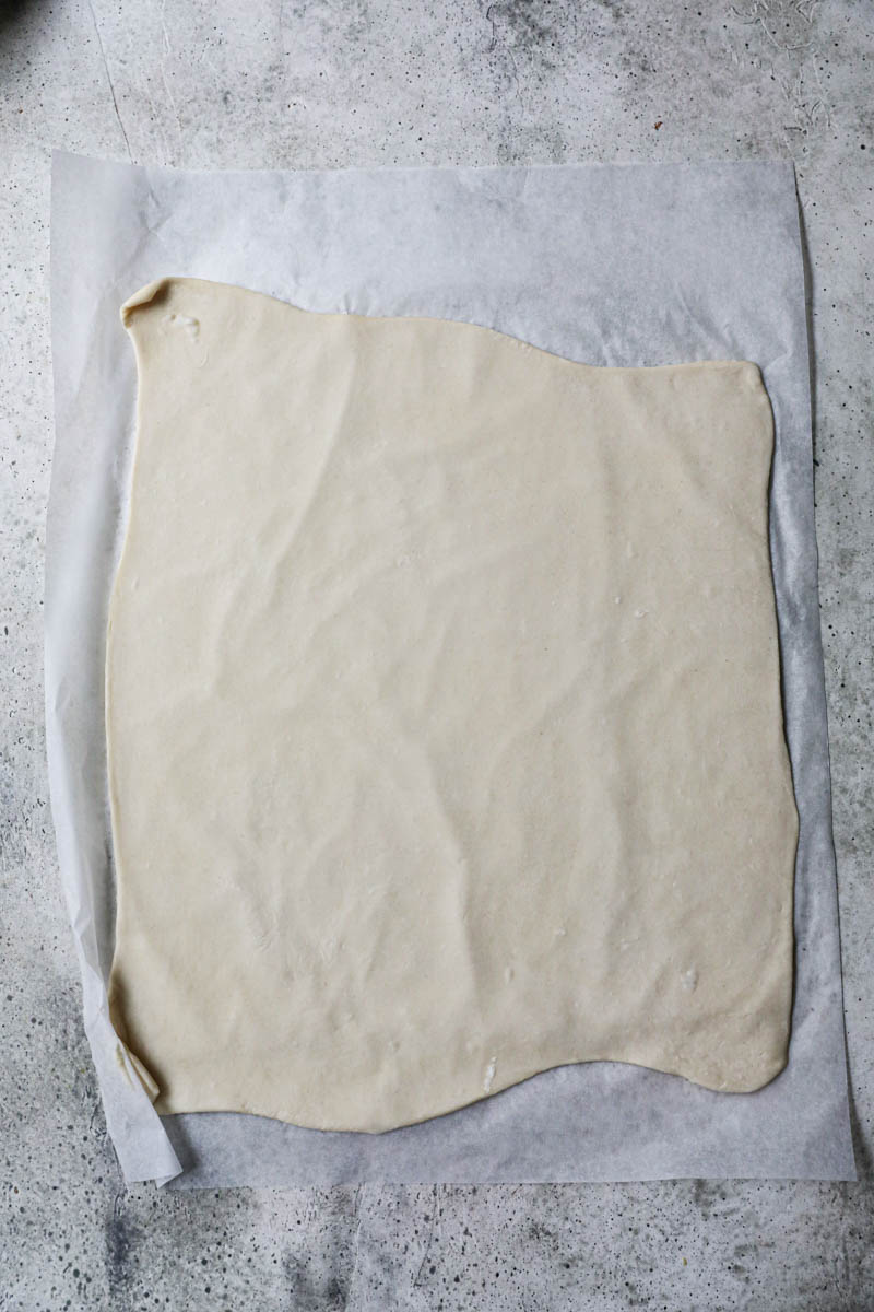 The rolled out crust on top of a parchment paper.