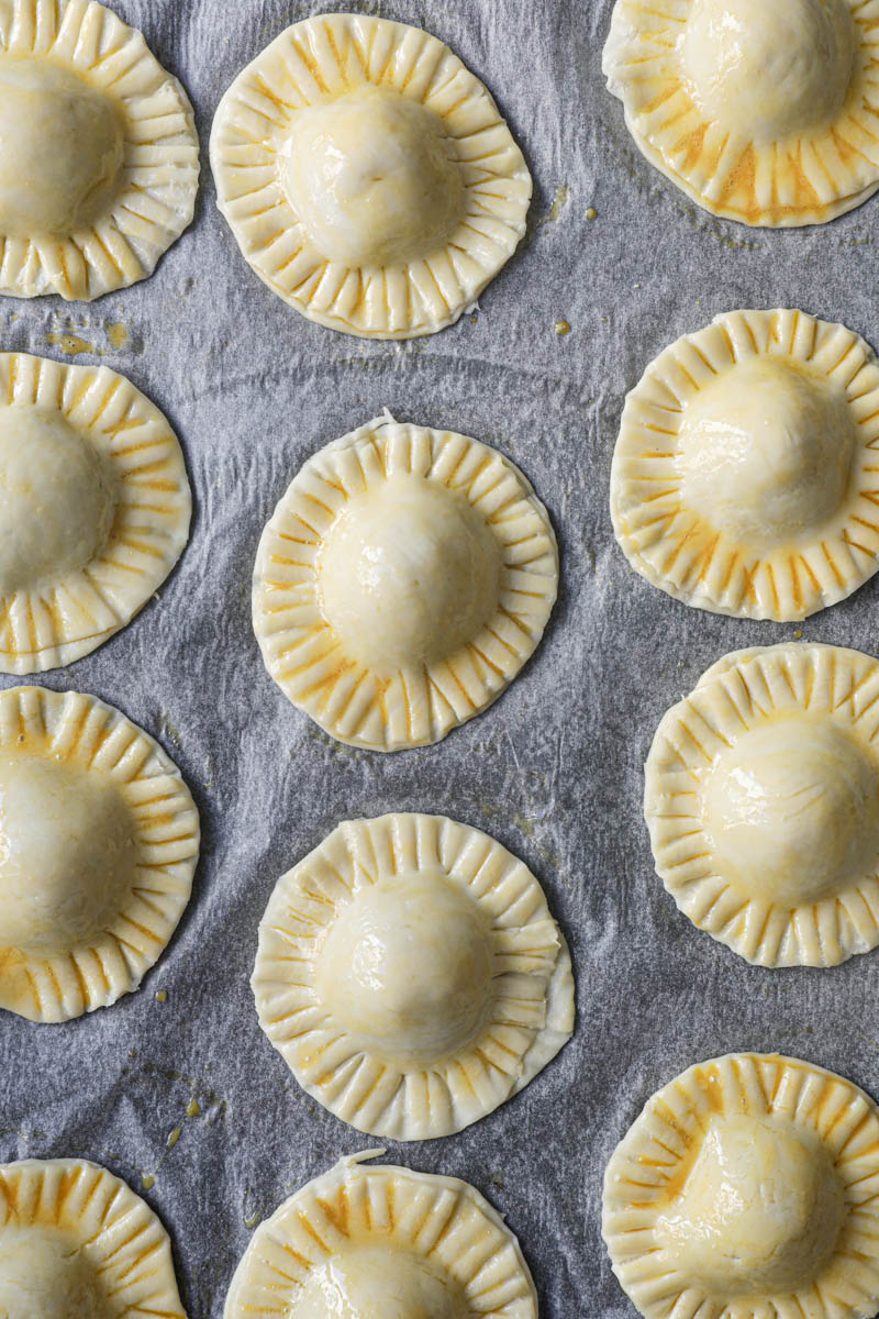 The chocolate pudding raspberry hand pies brushed with egg wash placed on a baking tray lined with parchment paper.