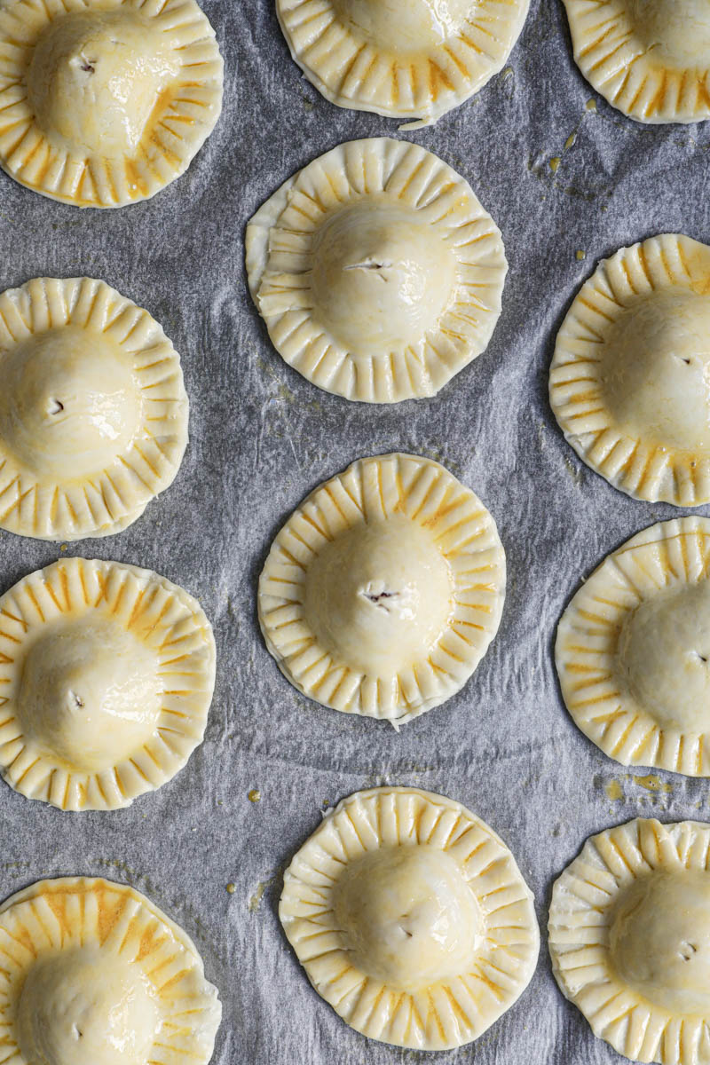 The chocolate pudding raspberry hand pies brushed with egg wash and with an insicion made at the centre, placed on a baking tray lined with parchment paper.