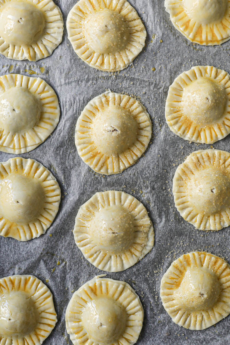 The chocolate pudding raspberry hand pies sprinkled with brown sugar placed on a baking tray lined with parchment paper.