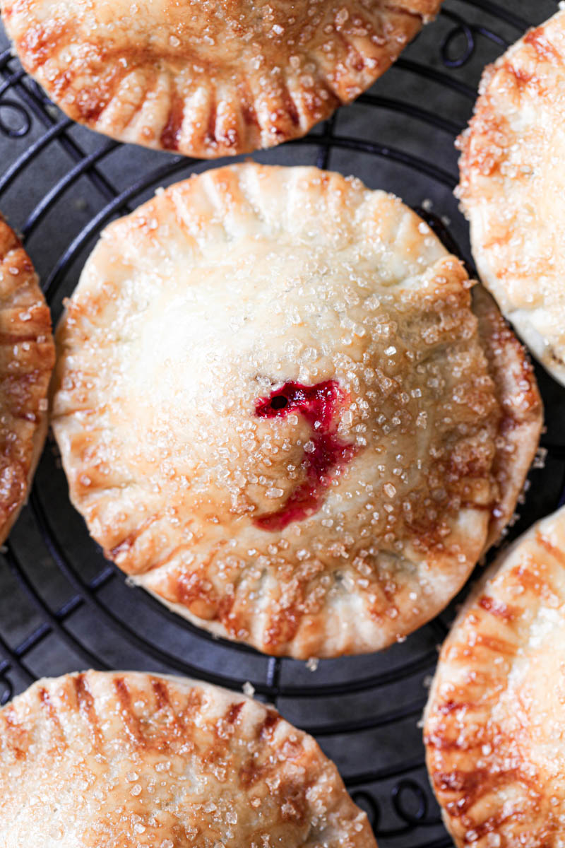 Macro shot of one baked chocolate raspberry mini hand pie with others around it.