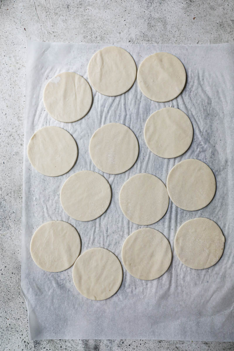 THe cut out pastry discs on top of a piece of parchment paper.