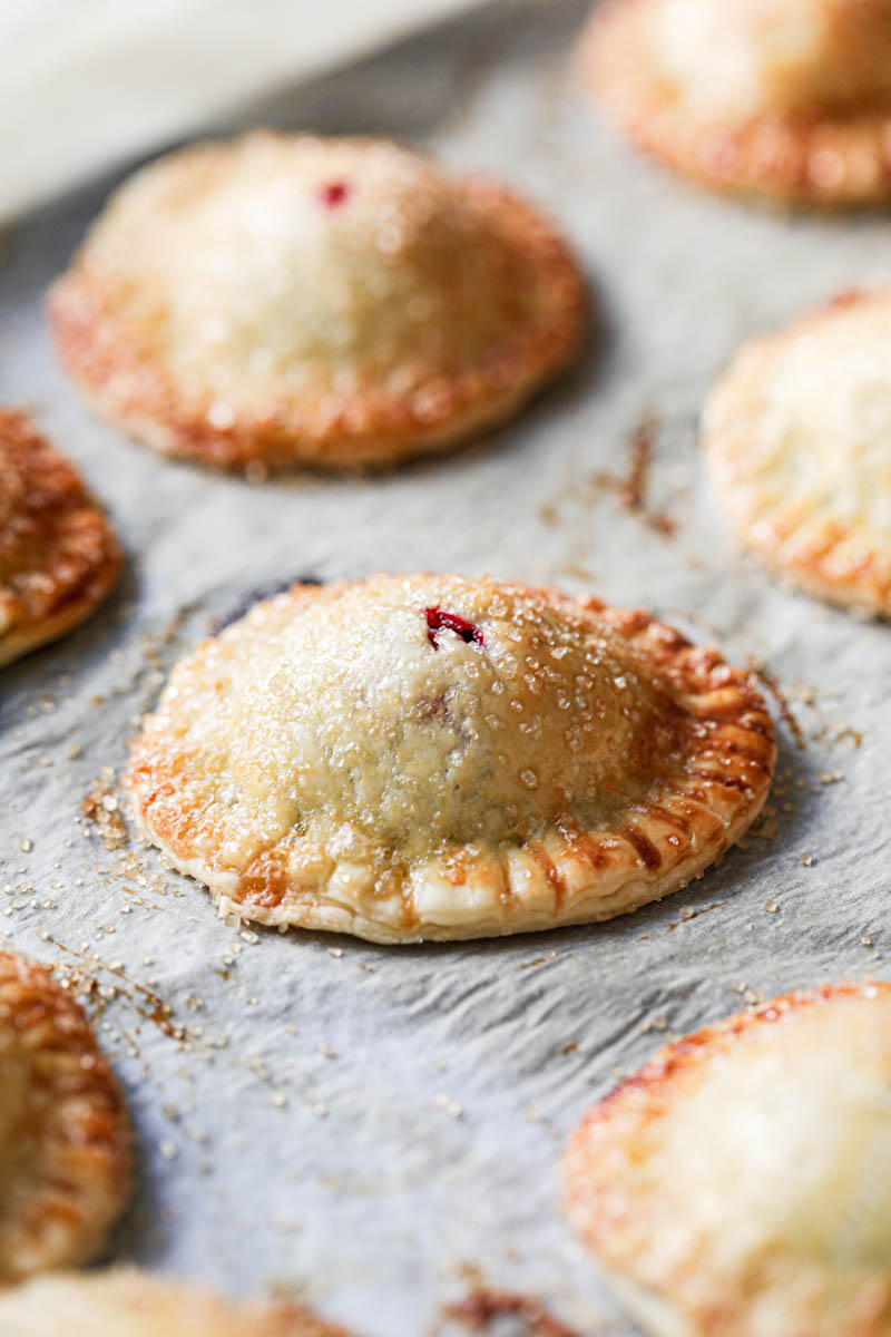 Closeup of the chocolate pudding raspberry hand pies on the baking tray lined with parchment paper as they were removed from the oven.