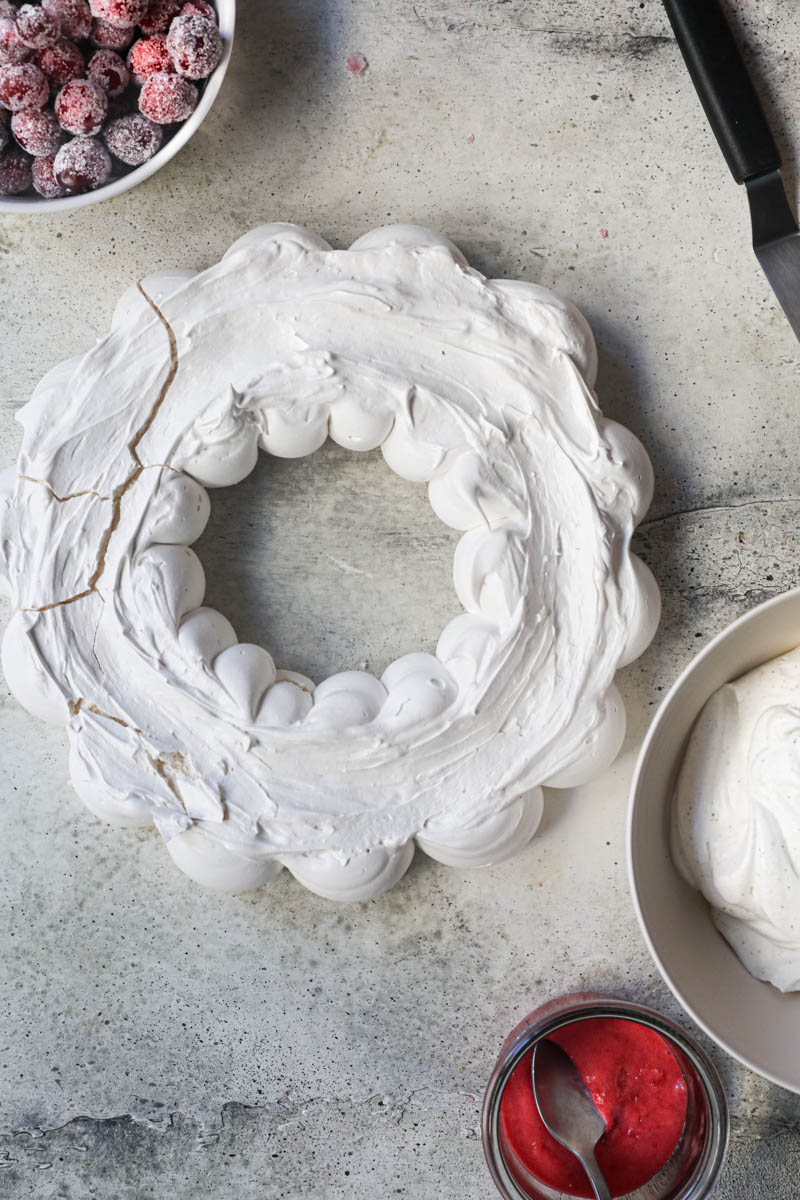 The baked pavlova wreath with some sugar cranberries on the left top corner of the frame.